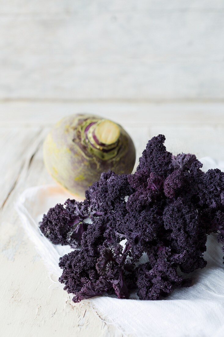 Purple curly kale and a turnip on a linen cloth