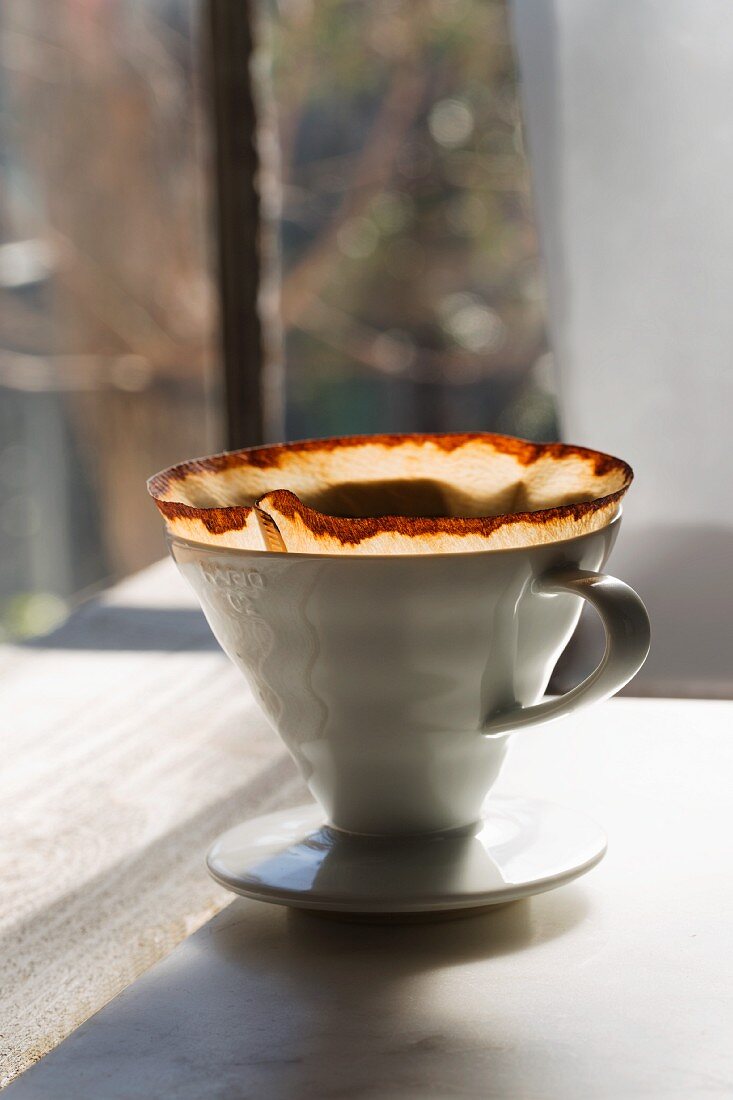 A used porcelain coffee filter with a paper filter