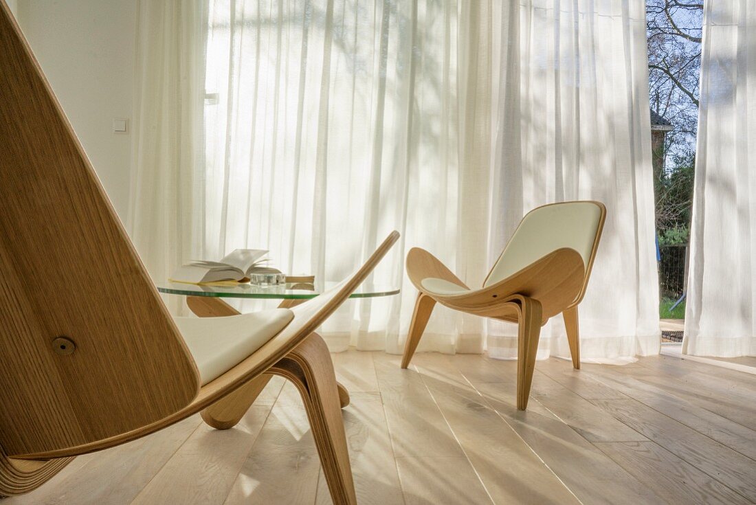 Wegner Shell Chair on oak floor in front of windows with airy curtains