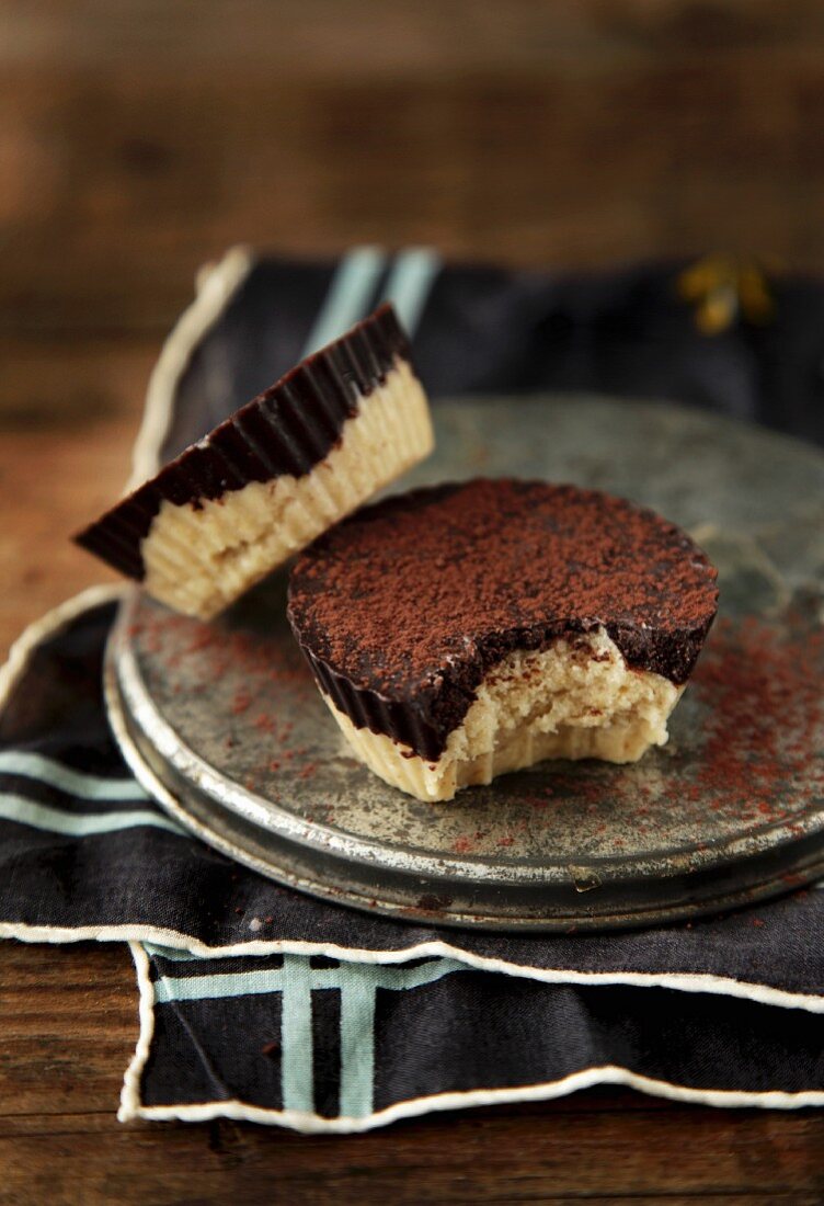 Two vegan chocolate coconut tartlets, one with a bite taken out