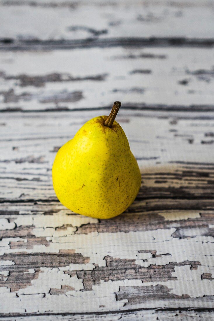 A yellow pear on a rustic wooden table