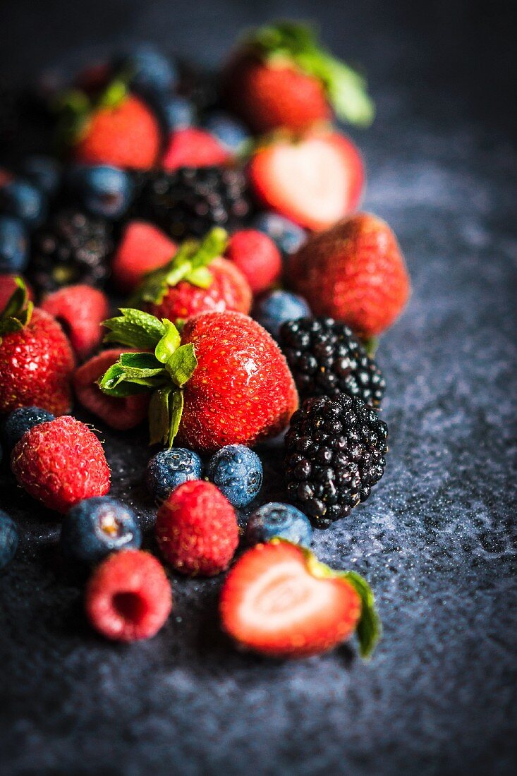 Various berries on a rustic black surface