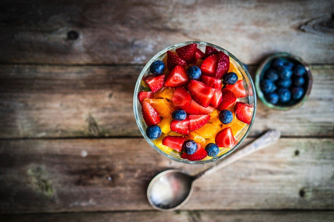 Colourful fruit salad in a jar on rustic wooden surface