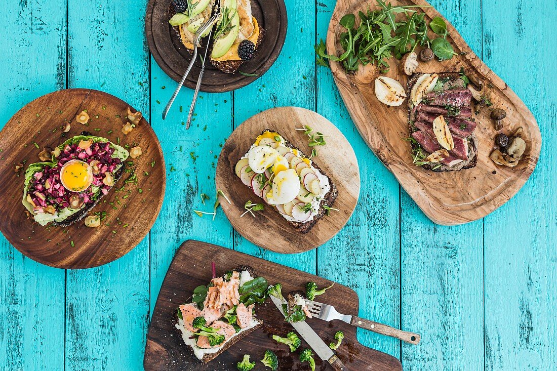 Various open sandwiches on rustic bread boards