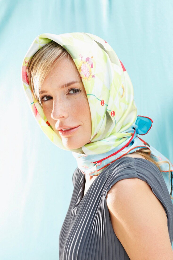 A young woman wearing a grey pleated top with a colourful headscarf