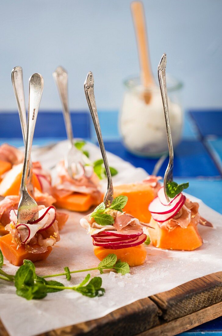 Papaya canapés with radishes, prosciutto and mint