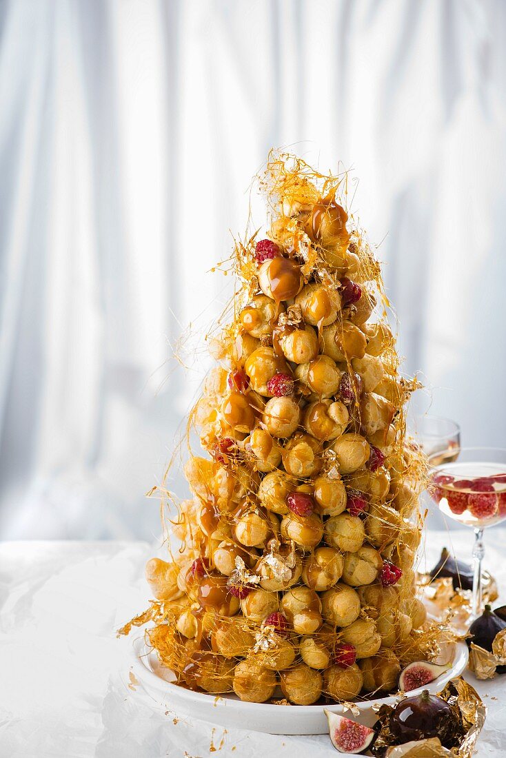 Christmas croquembouche with raspberries and figs wrapped in gold leaf