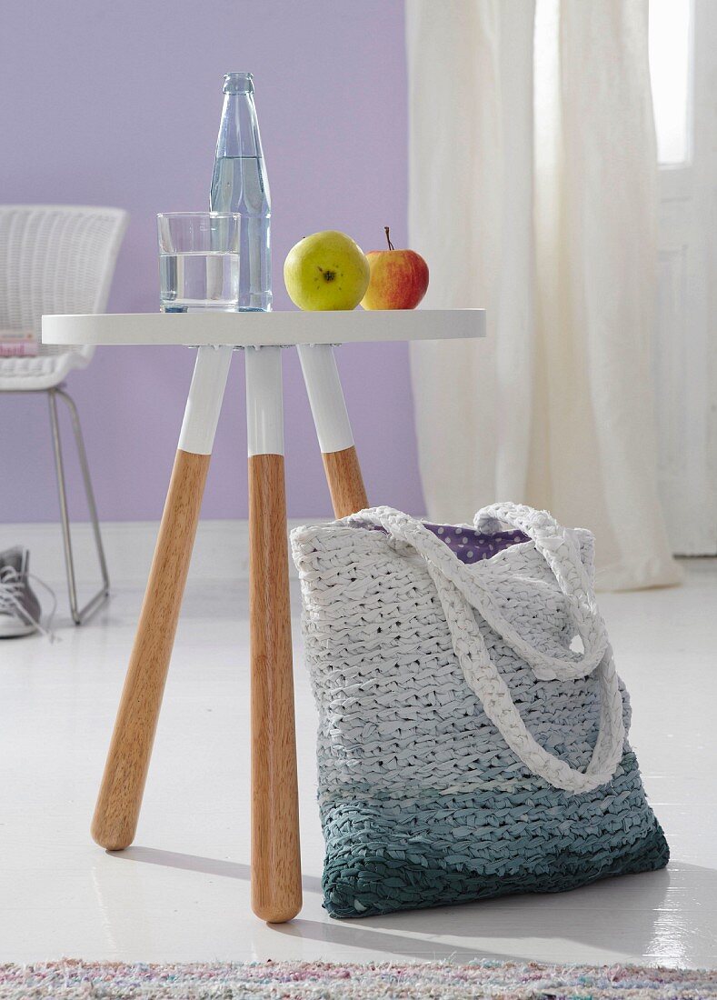 Einkaufstasche aus Stoffstreifen gehäkelt mit Farbverlauf neben Hocker im Dip-Dye Style