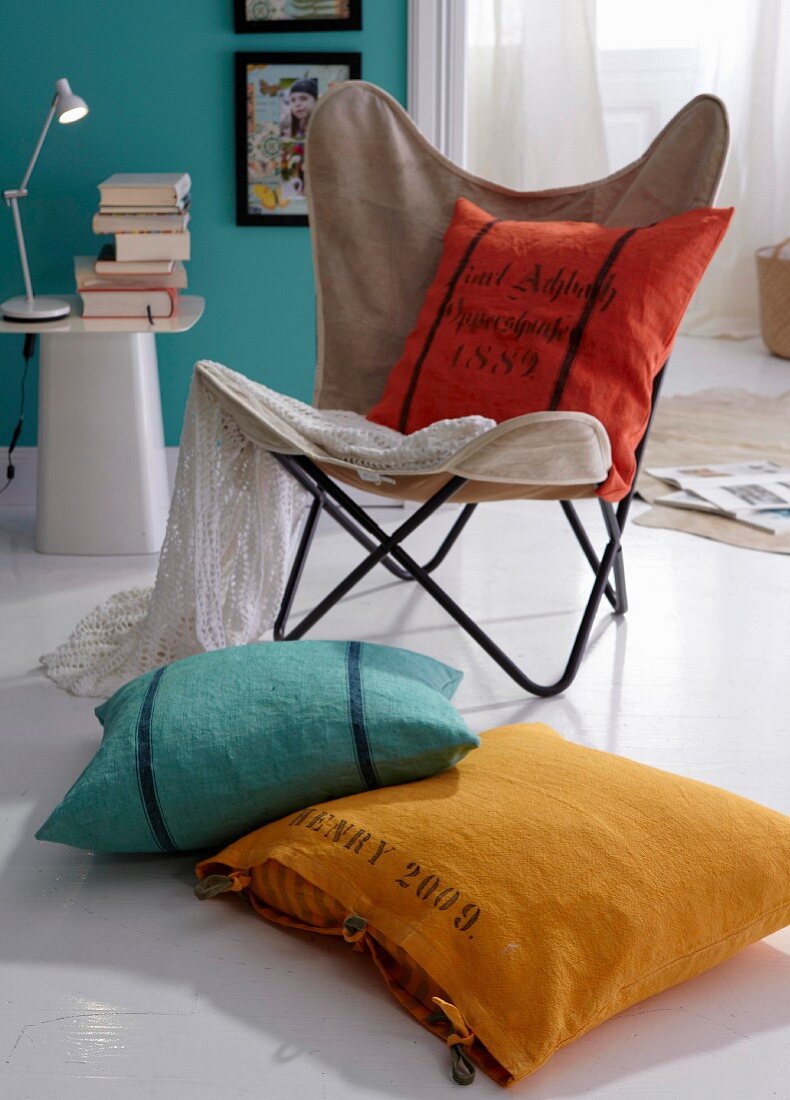 Colourful cushions on butterfly armchair and on the floor