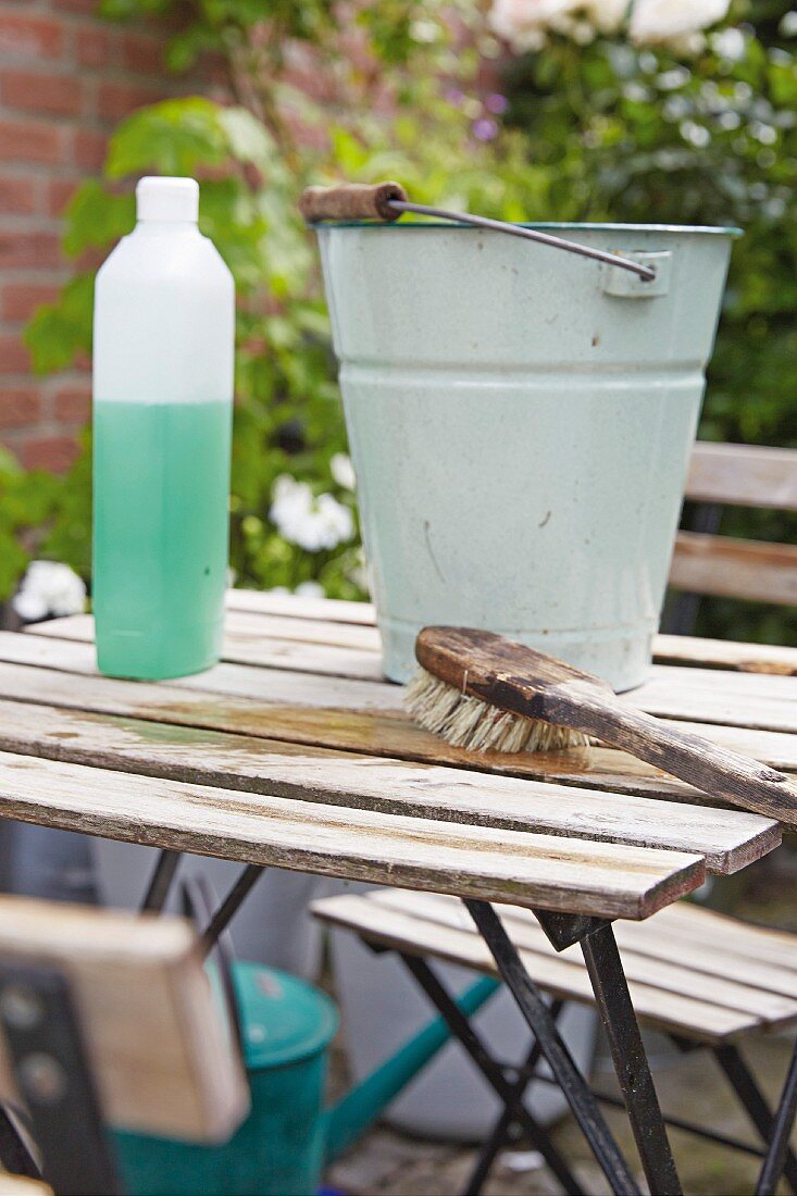Frühjahrsputz auf der Terrasse, Vintage Metalleimer und Putzutensilien auf Gartentisch