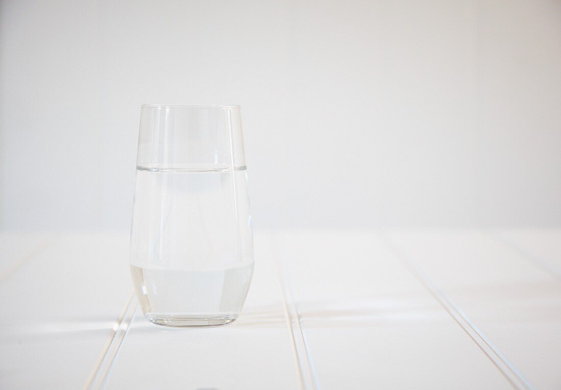 Ein Wasserglas auf weißem Holztisch
