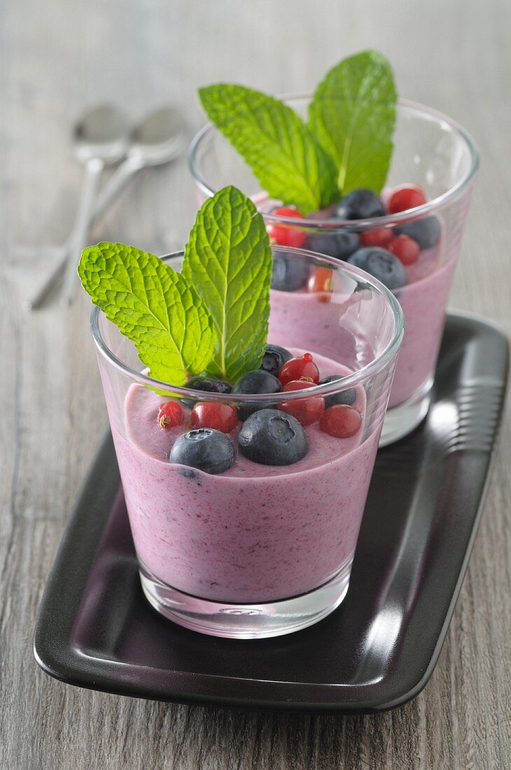Joghurt mit Heidelbeeren, roten Johannisbeeren und Minze im Glas