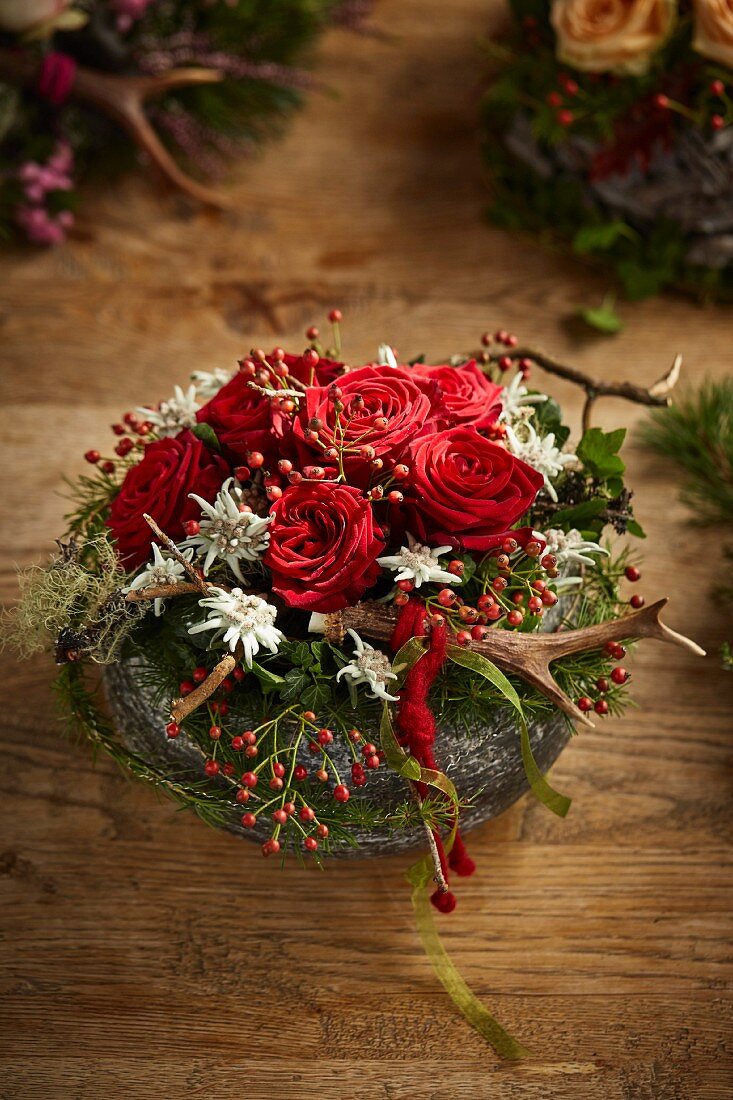 Alpine-style arrangement of roses, antlers, snowberries and edelweiss