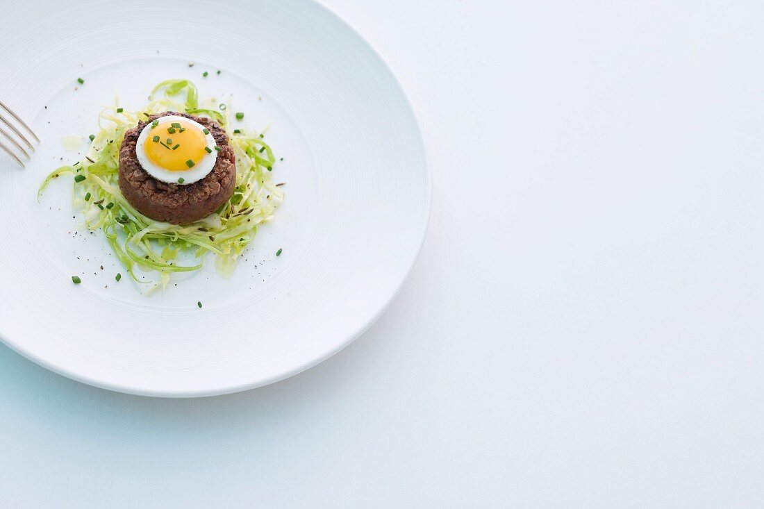 Fried beef tartare with fried quail's egg on a bed of pointed cabbage