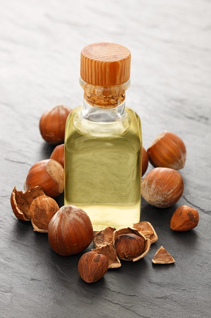 A bottle of hazelnut oil surrounded by hazelnuts