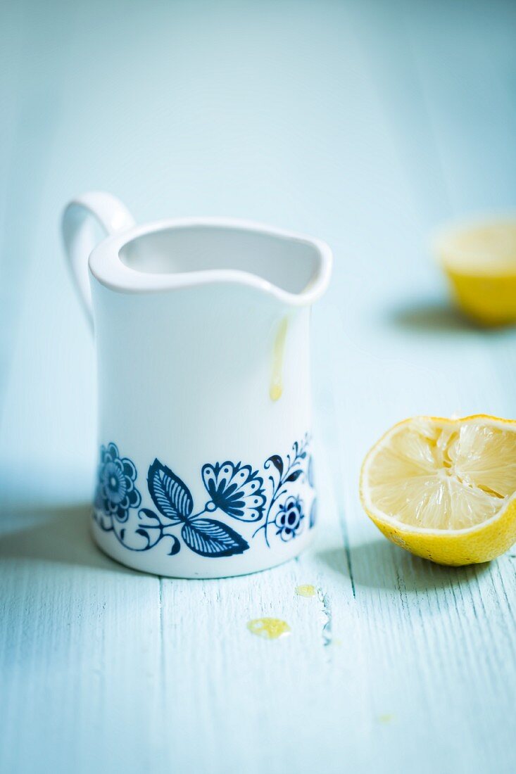 A retro jug of lemon dressing next to a juiced lemon half