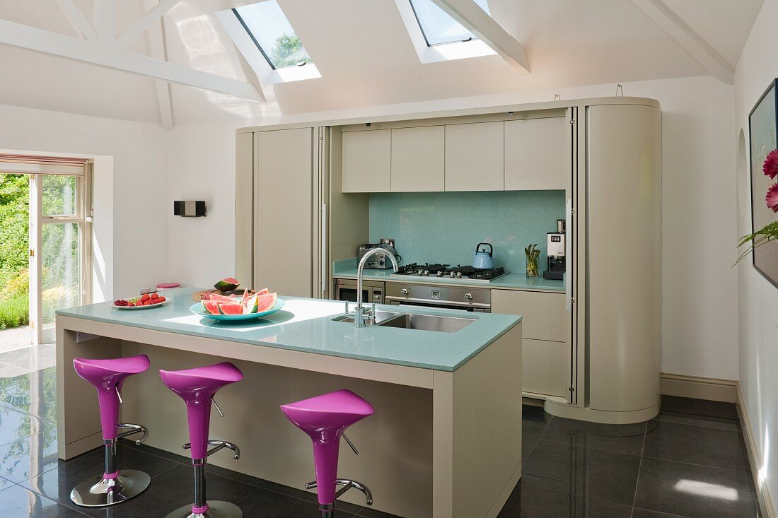 Island counter with bar stools and fitted counter with sliding door in modern kitchen