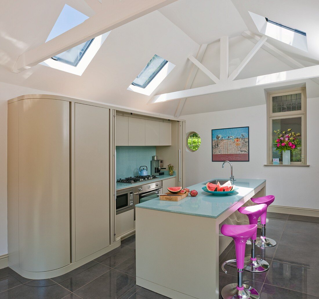 Island counter with bar stools and fitted counter with sliding door in modern kitchen