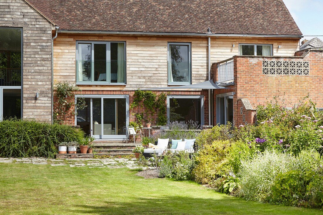 Modern country house with clapboard facade, extension with roof garden and sunny garden