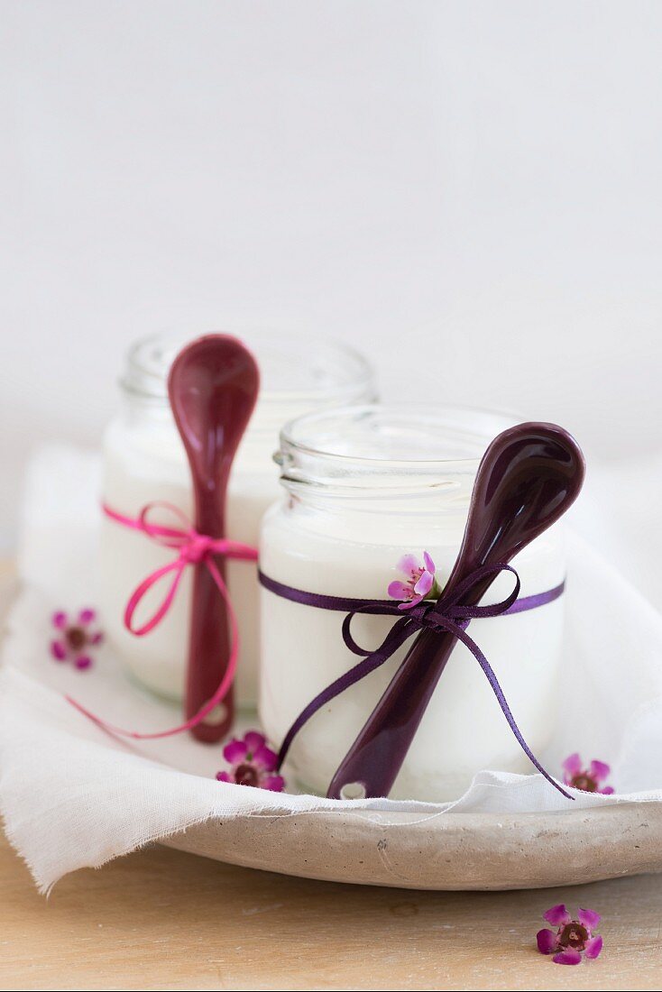 Selbstgemachte Joghurts im Glas mit Bändern und Löffeln