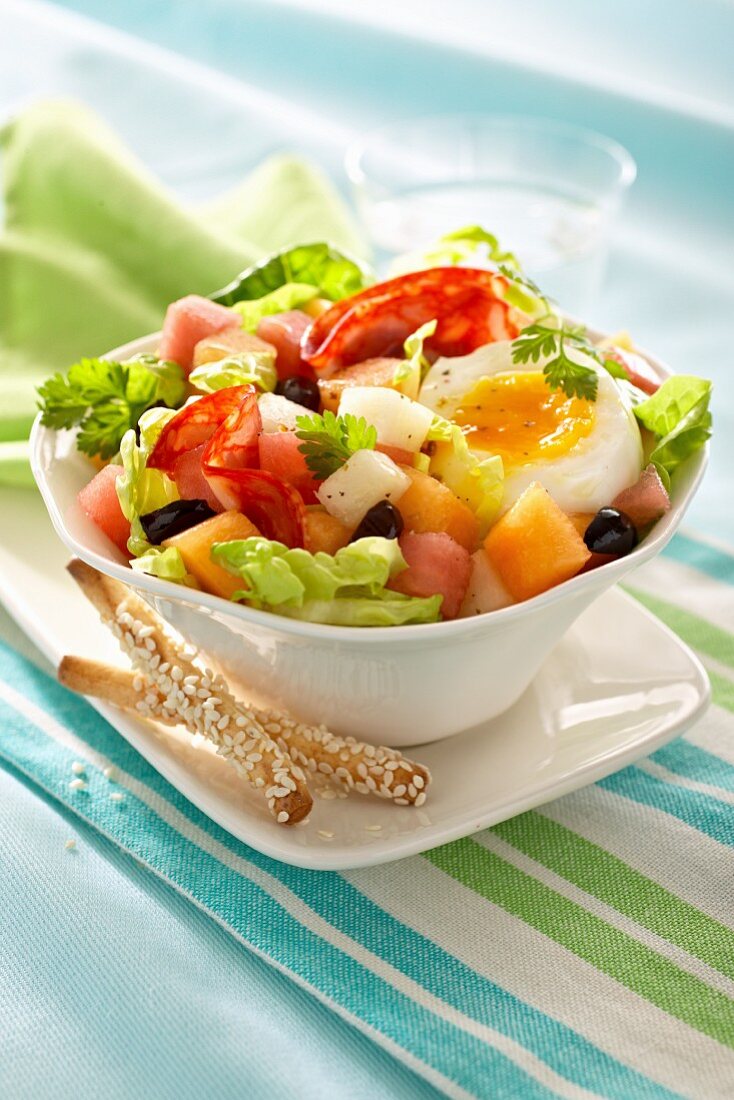 Salat mit Salami, halbem Ei, Melone und Oliven
