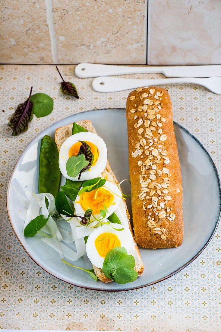 An open egg sandwich with mange tout