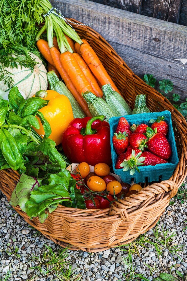 A basket of fresh vegetables, berries and herbs