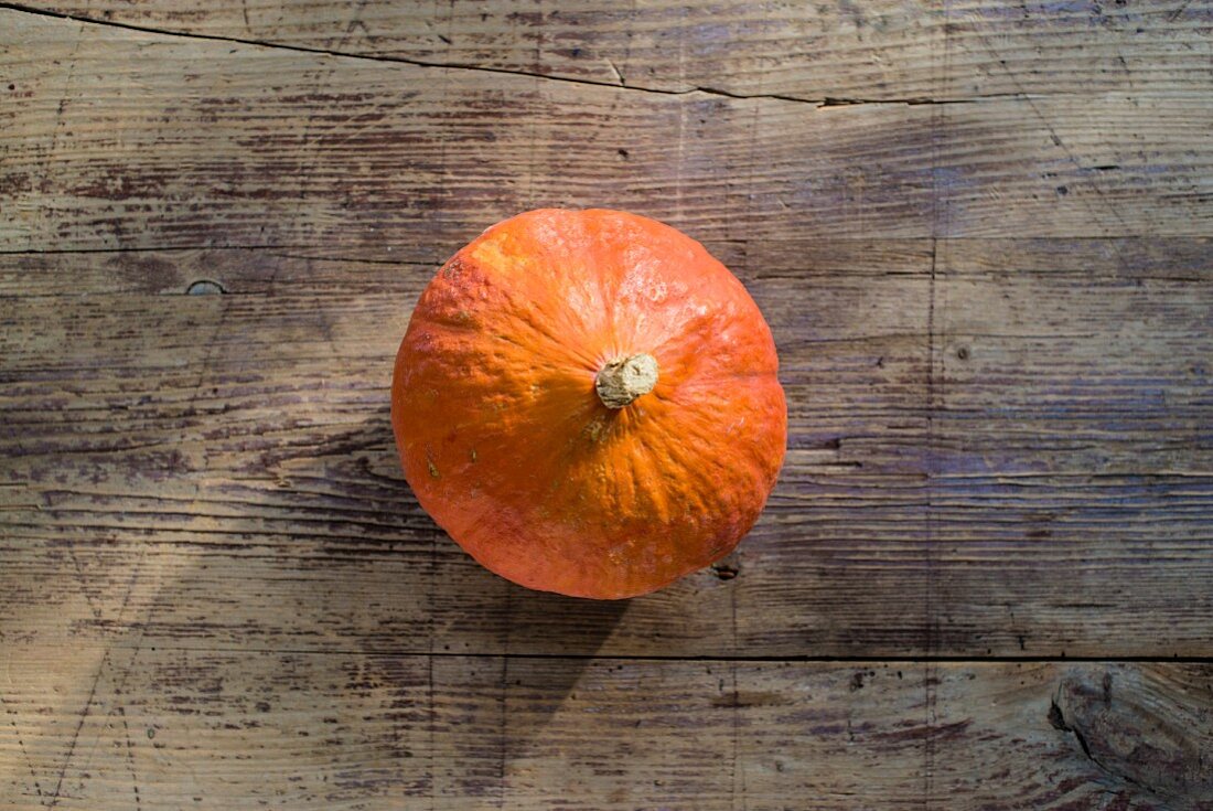 A Hokkaido pumpkin on a wooden table (seen from above)