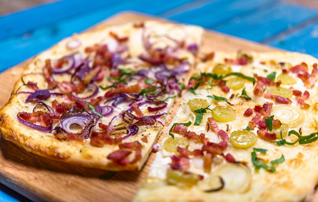 Tarte flambée with two different toppings on a wooden board