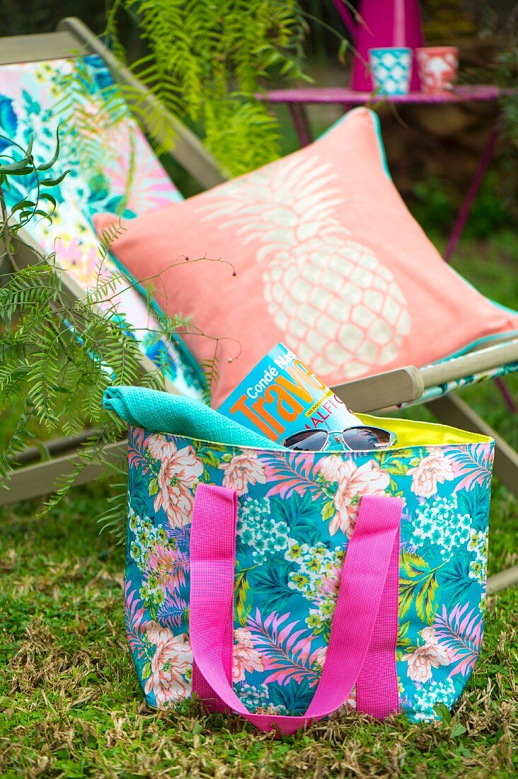 Sommerlicher Sitzplatz mit Liegestuhl, Kissen und Strandtasche