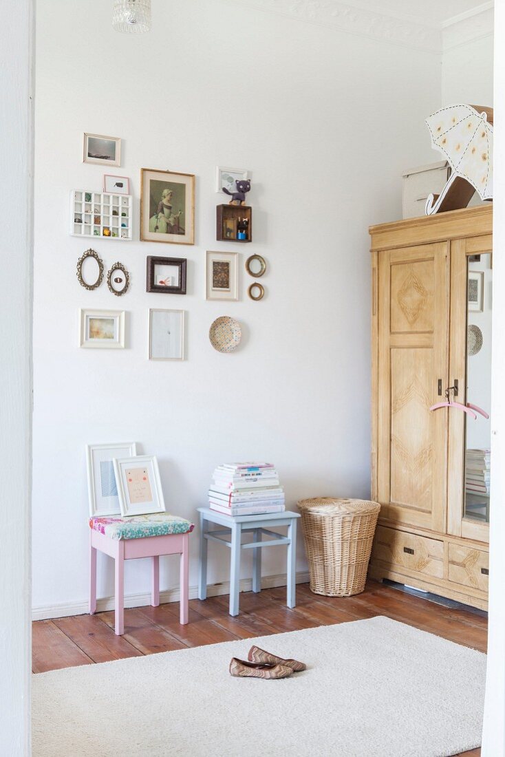 Pastel stools below gallery of pictures next to old wardrobe