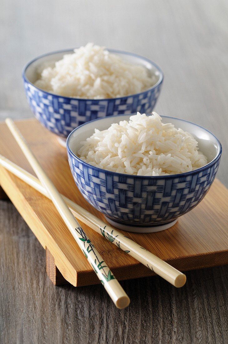 Cooked rice in Oriental bowls with chopsticks