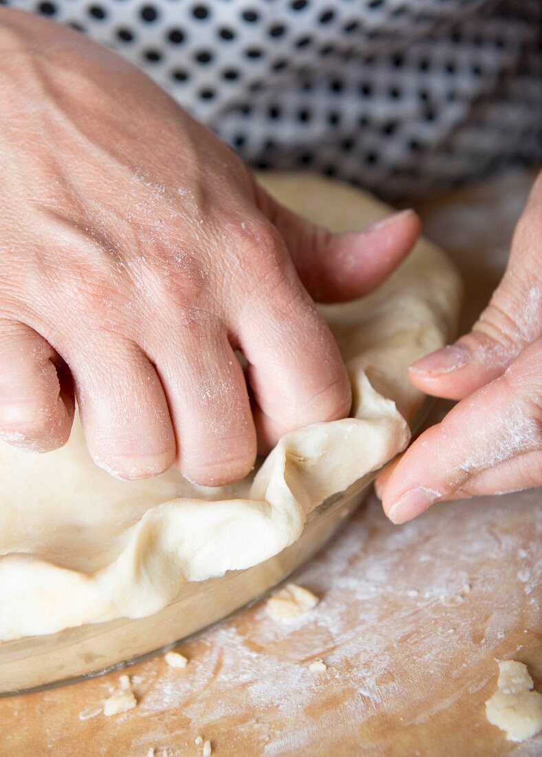 Doublecrossed pie being made: pastry lid being pushed down by hand