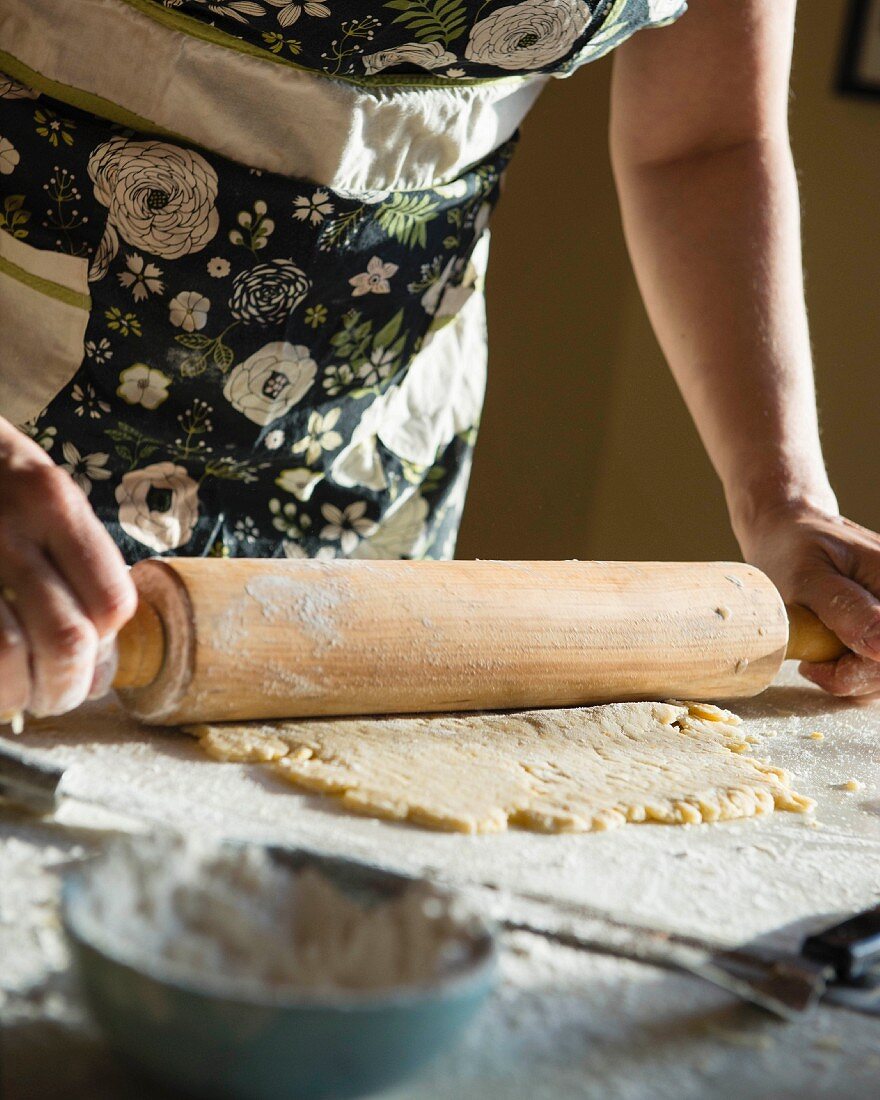 A woman rolling out shortcrust pastry