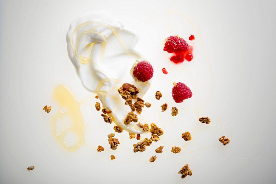 Muesli ingredients: yoghurt, raspberries, granola and honey (seen from above)