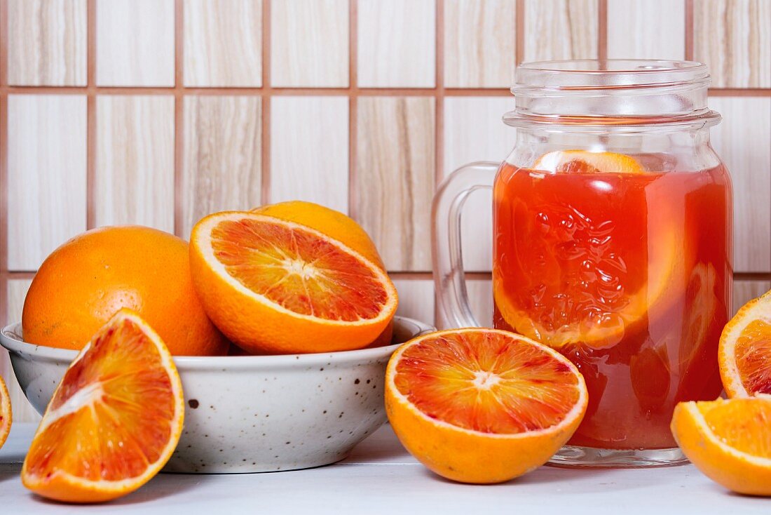 An arrangement of blood oranges and a carafe of blood orange juice