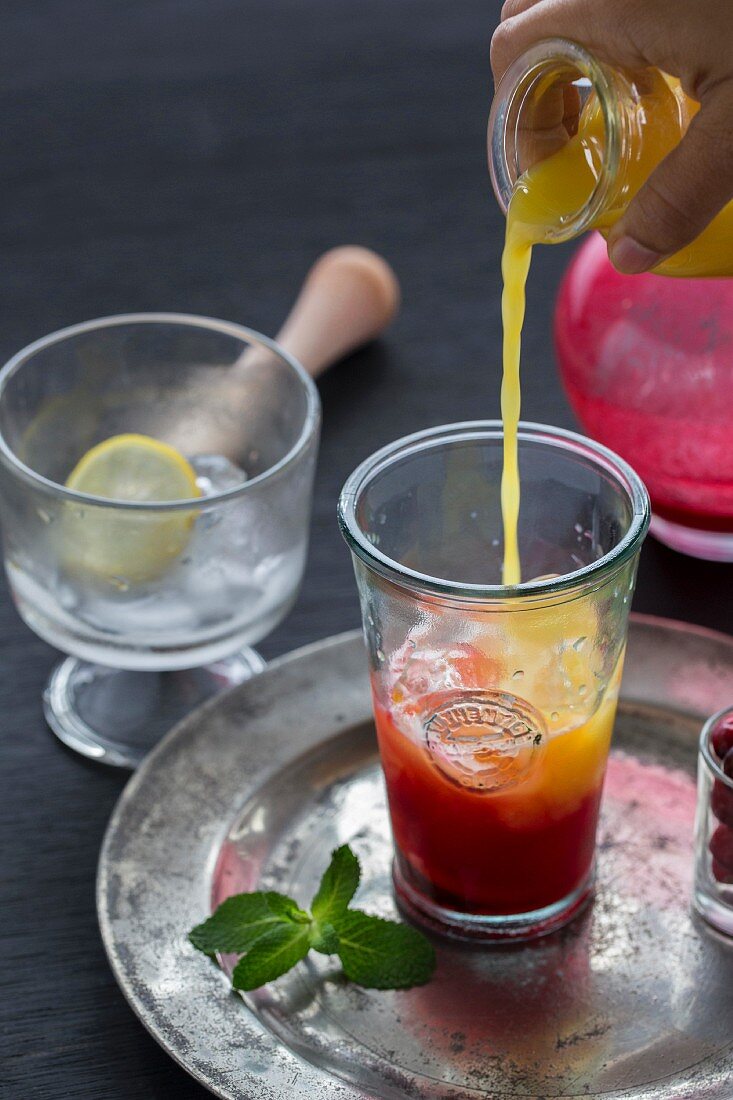 A cranberry mojito being poured