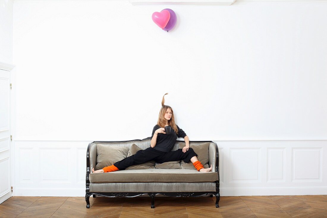 A young woman sitting on an old sofa with her legs wide open