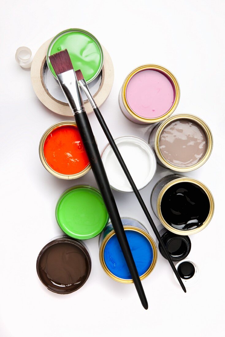 Various pots of paint, paintbrushes and masking tape seen from above