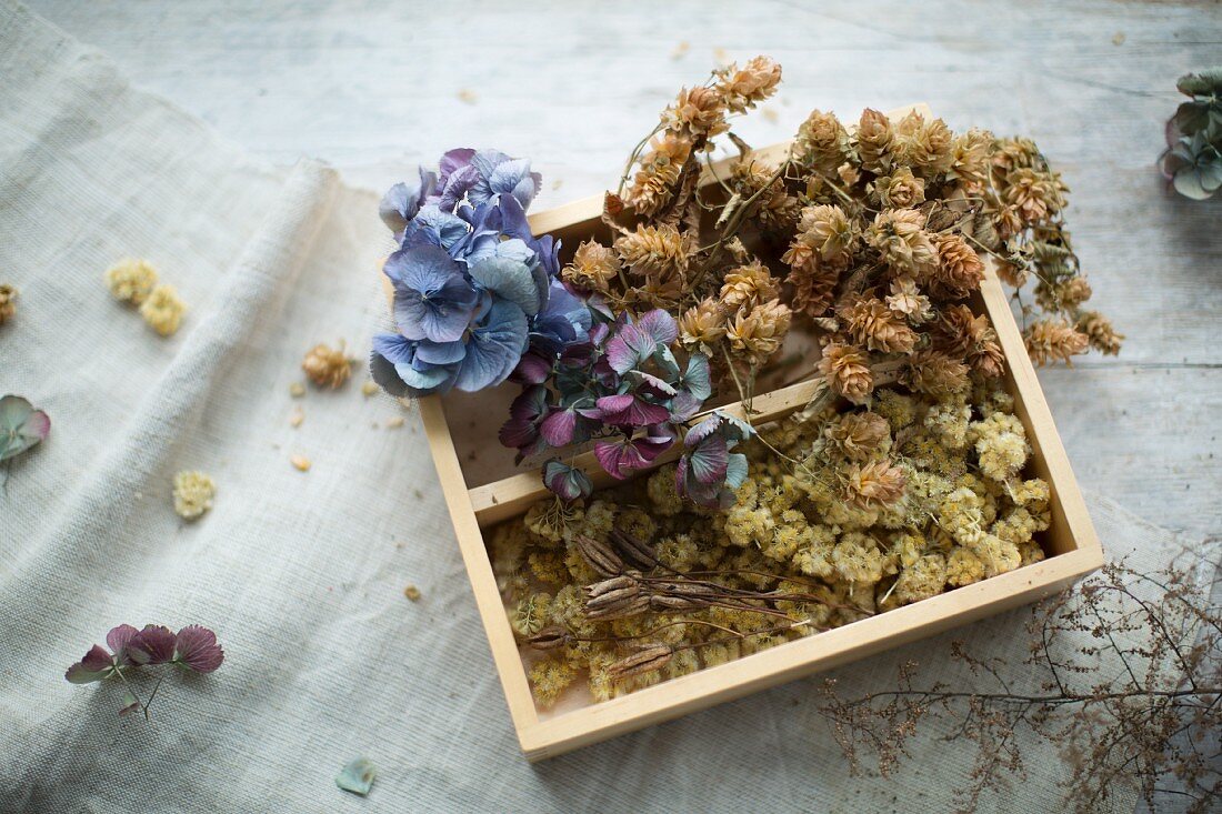 Trockenblumen in einer Holzkiste auf Leinentuch