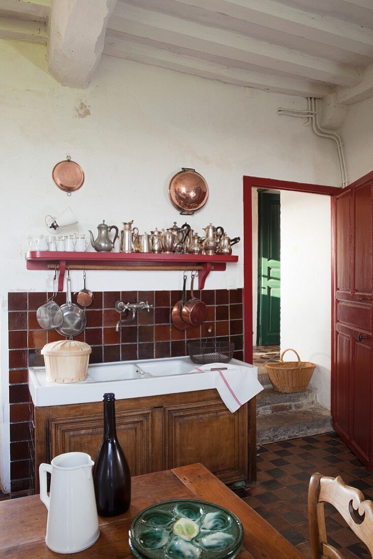 Küchenspültisch mit Holzunterschrank vor rot-braunem Fliesenspritzschutz