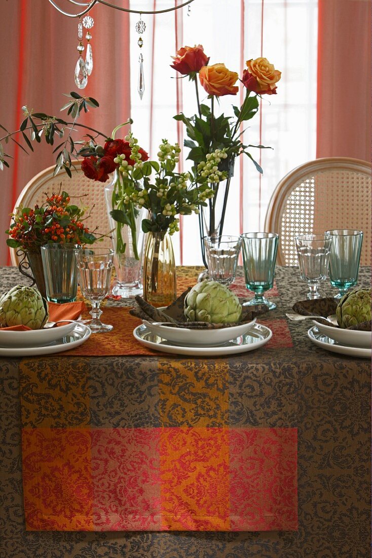 Table autumnally decorated with roses, bunches of berries and artichokes