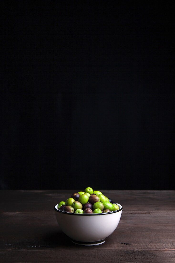 A bowl of olives on a wooden table