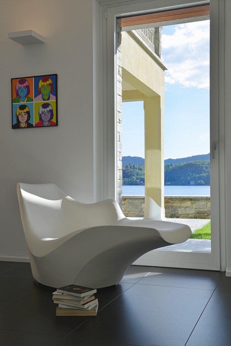 Sculptural designer chaise in front of glass door