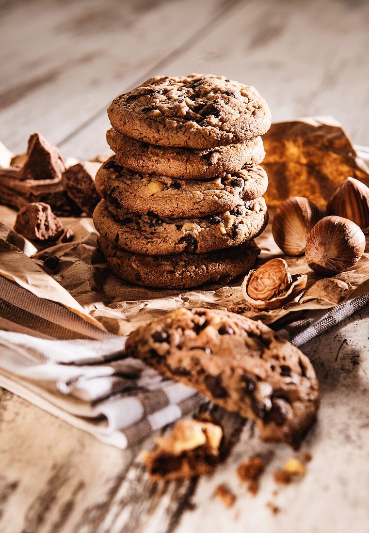 Chocolatechip Cookies und Haselnüsse auf braunem Papier und Geschirrtuch