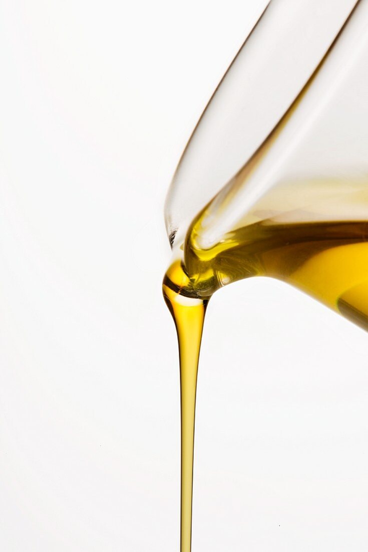 Oil being poured from a carafe against a white background