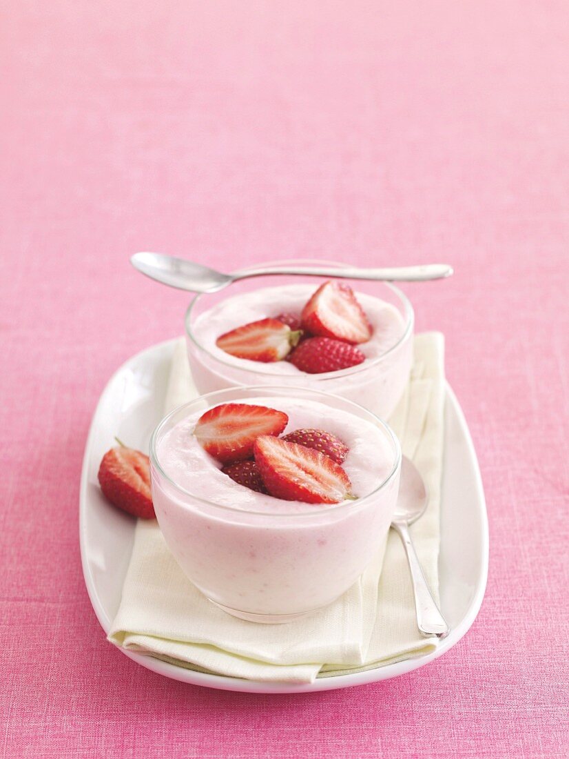 Strawberry yoghurt with fresh strawberries in two dessert bowls