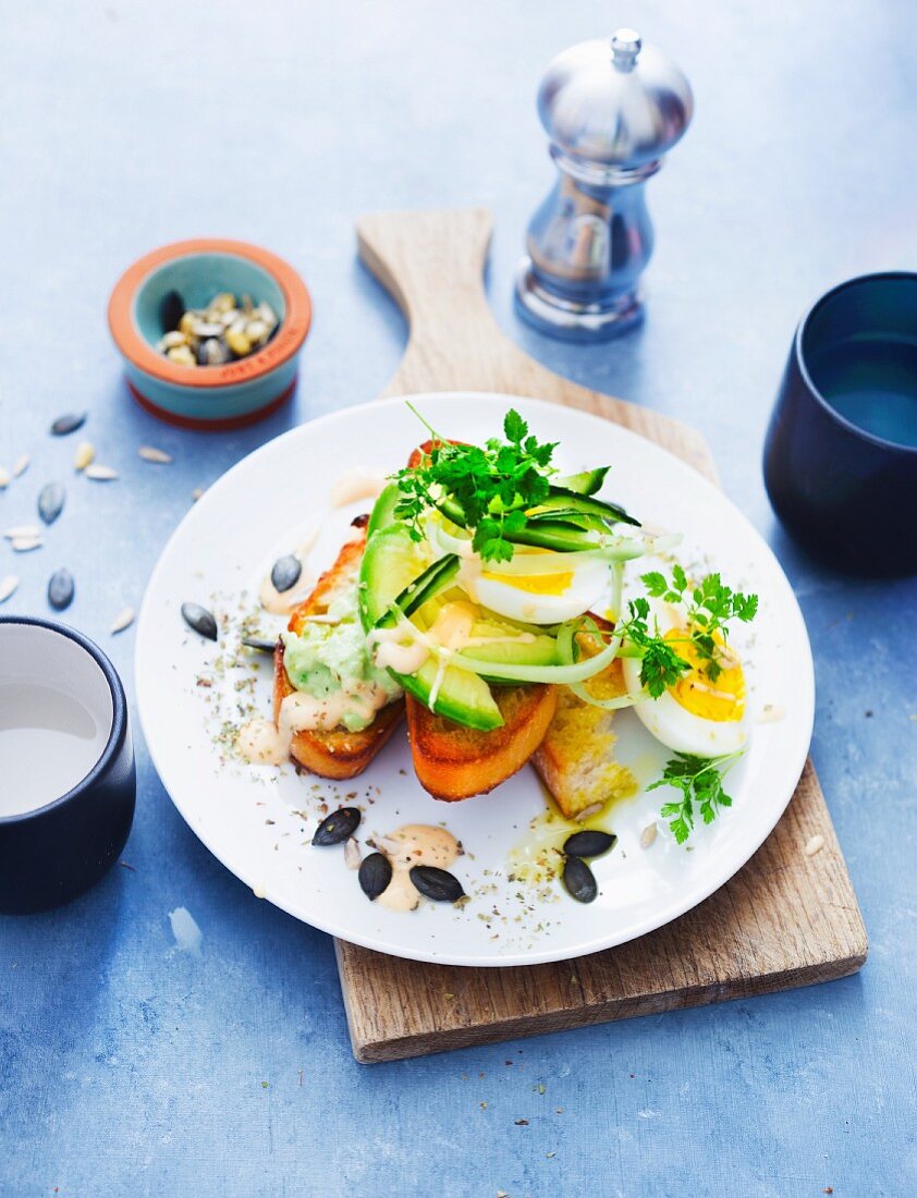 Grilled bread topped with avocado, egg and yoghurt sauce