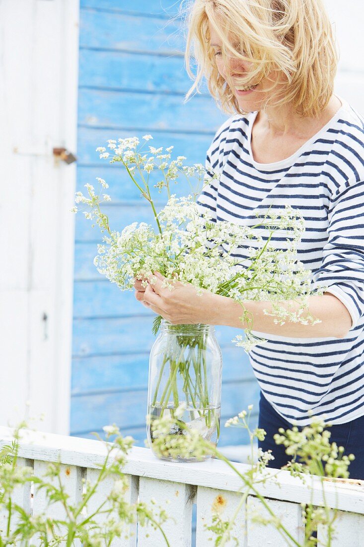 Woman wearing striped top arranging flowers in preserving jar