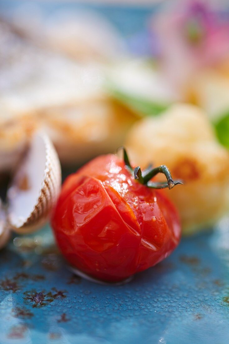 Roasted cherry tomato served with hake (close-up)